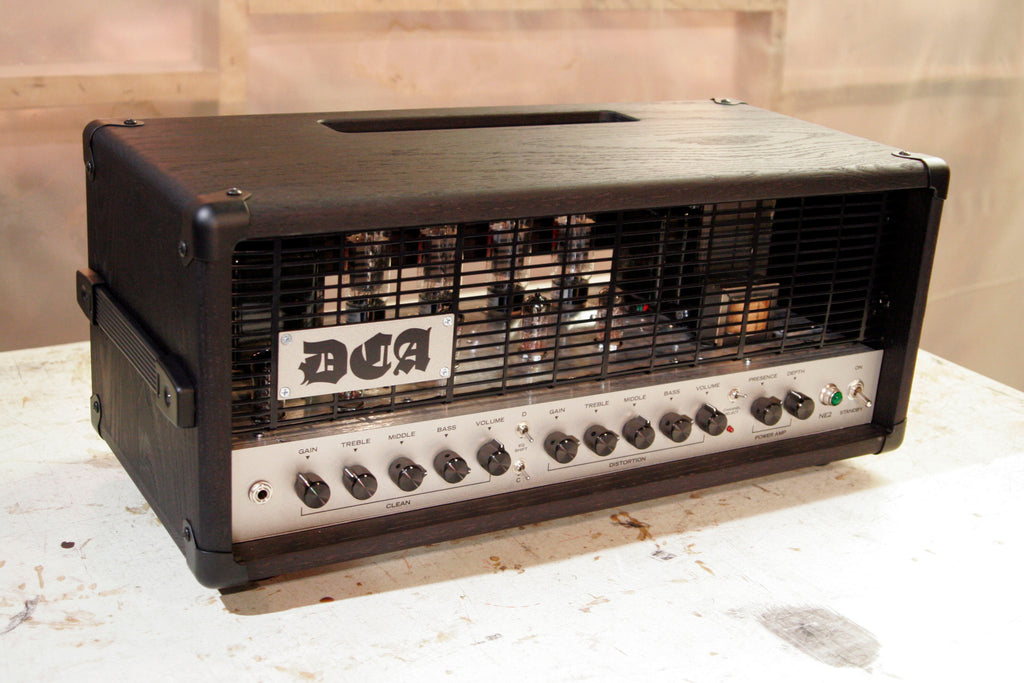 Guitar amplifier head with 'DCA' branding on a metal grill.